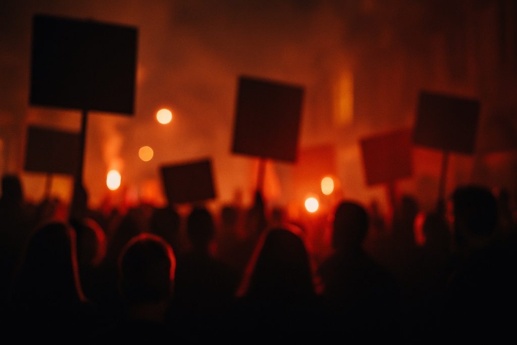 Blurred protest at night symbolizing moral blindness and a culture celebrating death.