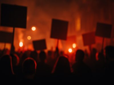 Blurred protest at night symbolizing moral blindness and a culture celebrating death.