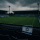 Jewish Discrimination in the UK shown by empty football stadium with Israeli flag draped over seat railing