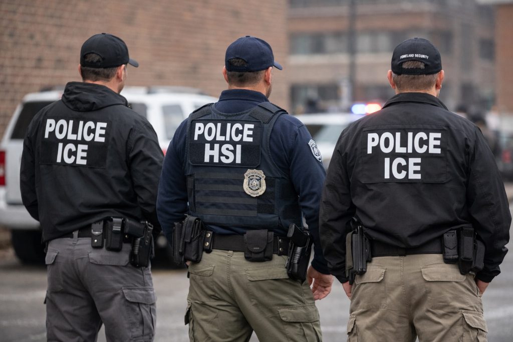 ICE agents standing calmly during a federal immigration enforcement operation